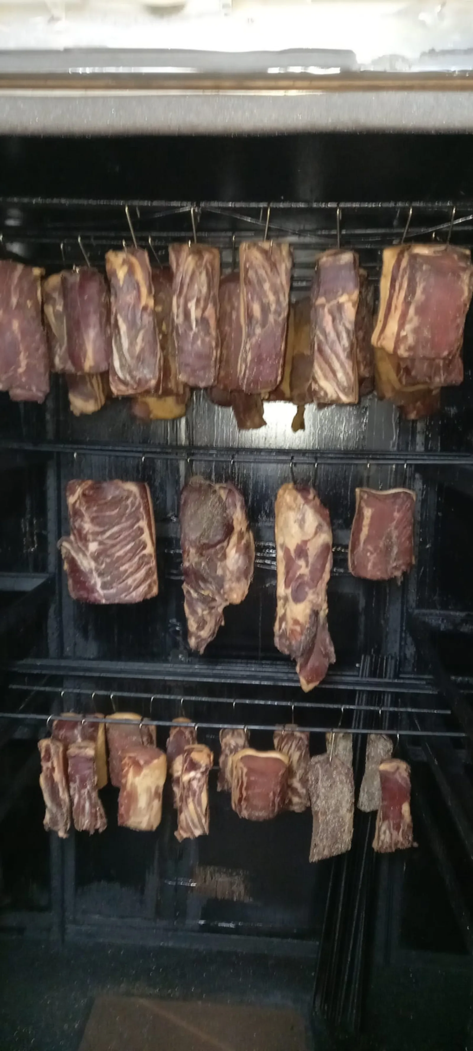 Speck und Karree hängend in der Räucherkammer